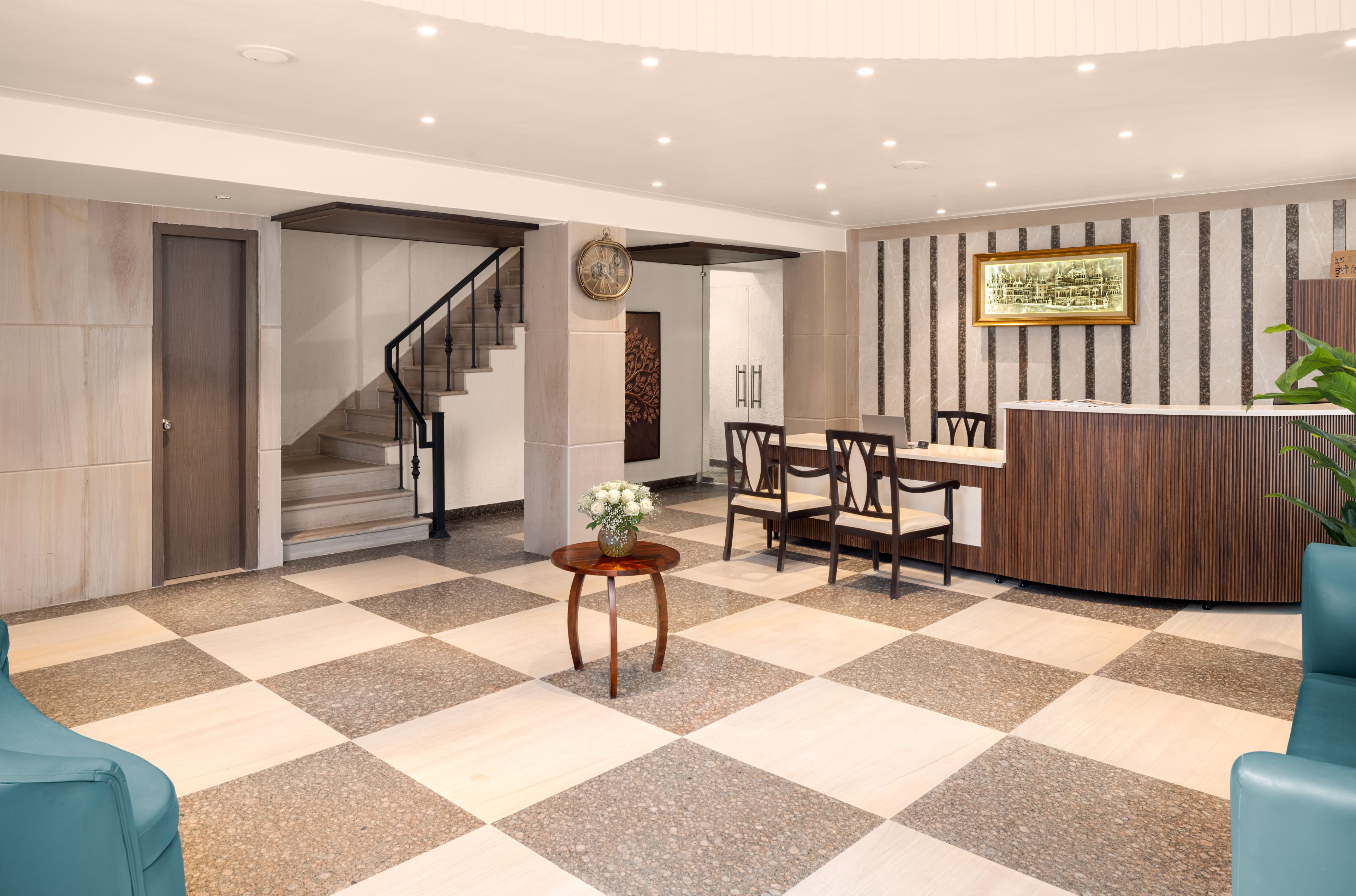 A hotel lobby with a checkered floor, a reception desk, a staircase, and a dining area.