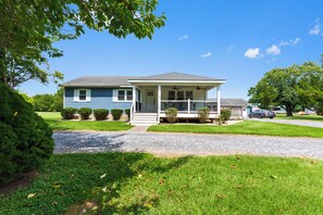 Ein zweigeschossiges Haus mit Veranda, Auffahrt und gepflegtem Rasen.
