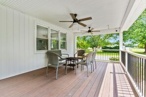 A covered porch with a ceiling fan, wooden flooring, and wicker chairs. - 2-Acre Retreat Near Ocean City + Game Room (Berlin)