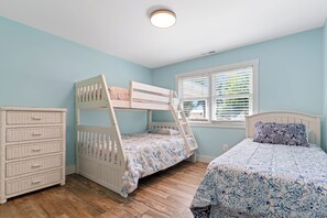 Ein Kinderstockbett mit einer Leiter, einer Kommode und einem Fenster mit Jalousien.