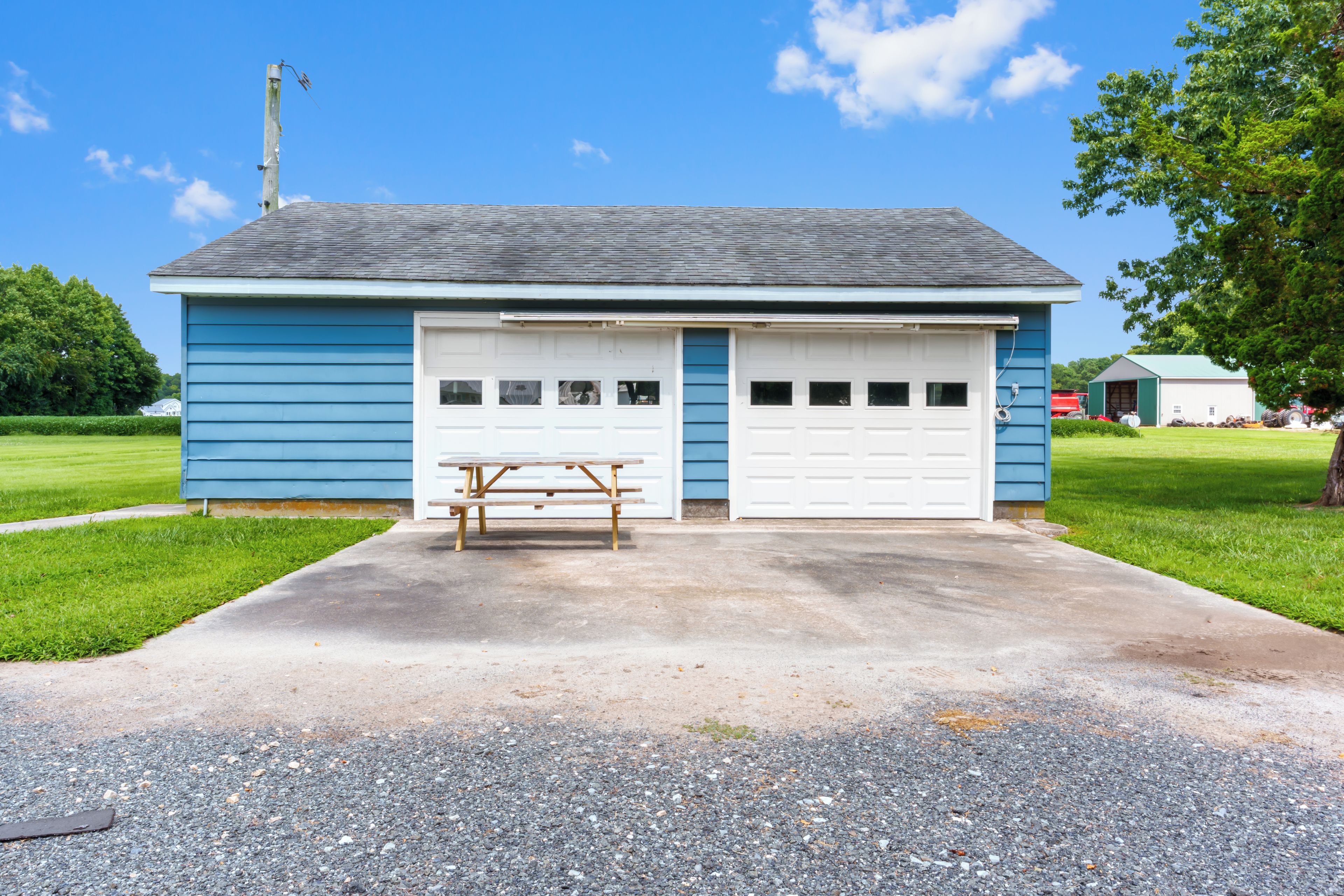 A single-story building with a garage, a picnic table, and a grassy area in front.