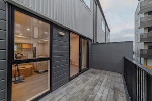 Ein modernes Gebäude mit Balkon, großen Fenstern und einem sichtbaren Innenbereich mit Küche und Essbereich.