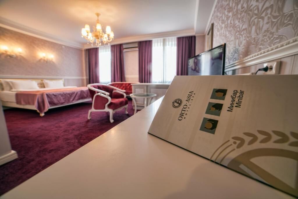 A hotel room with a bed, a chair, a desk, and a chandelier.