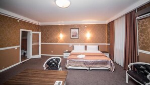 Quarto de hotel com uma cama, uma escrivaninha, uma cadeira e um banheiro visível por uma porta aberta.