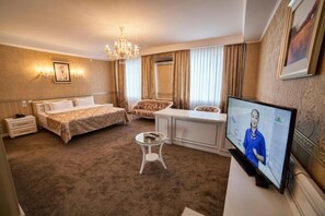 A hotel room with a bed, a desk, a television, and a small table. - Hotel Orto Asia Osh (Osh)