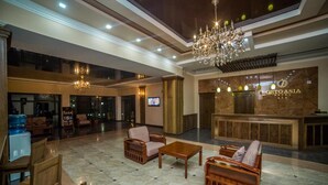Um saguão de hotel com uma mesa de recepção, área de estar e um candelabro.