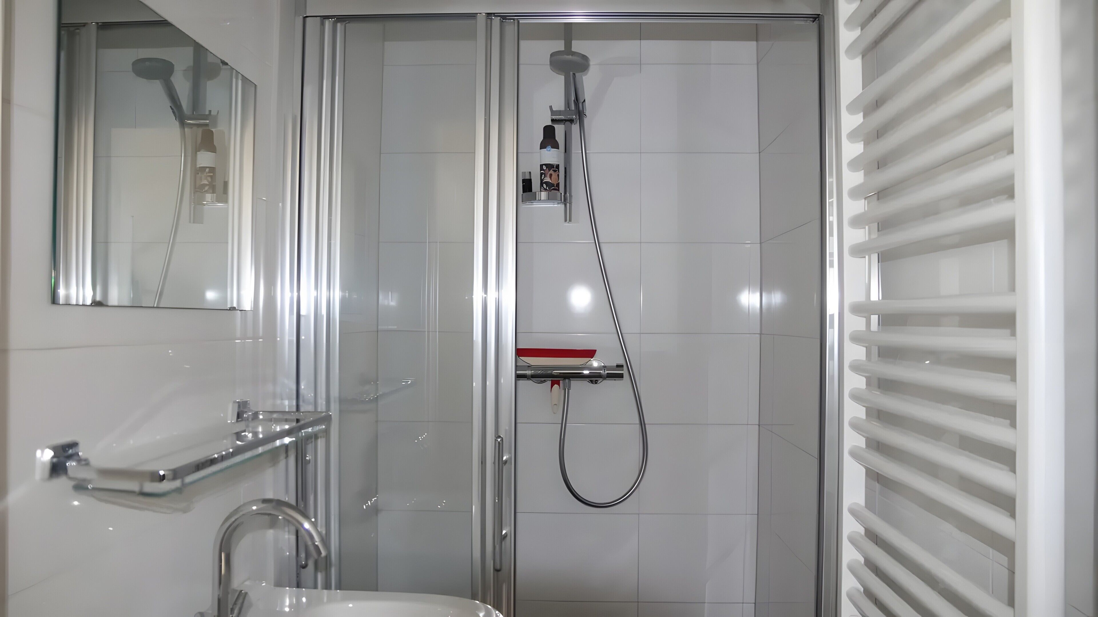 Ein modernes Badezimmer mit einer einteiligen Duschkabine, einem Waschbecken mit Chromarmatur und einem Spiegel darüber.