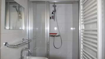 Ein modernes Badezimmer mit einer einteiligen Duschkabine, einem Waschbecken mit Chromarmatur und einem Spiegel darüber.