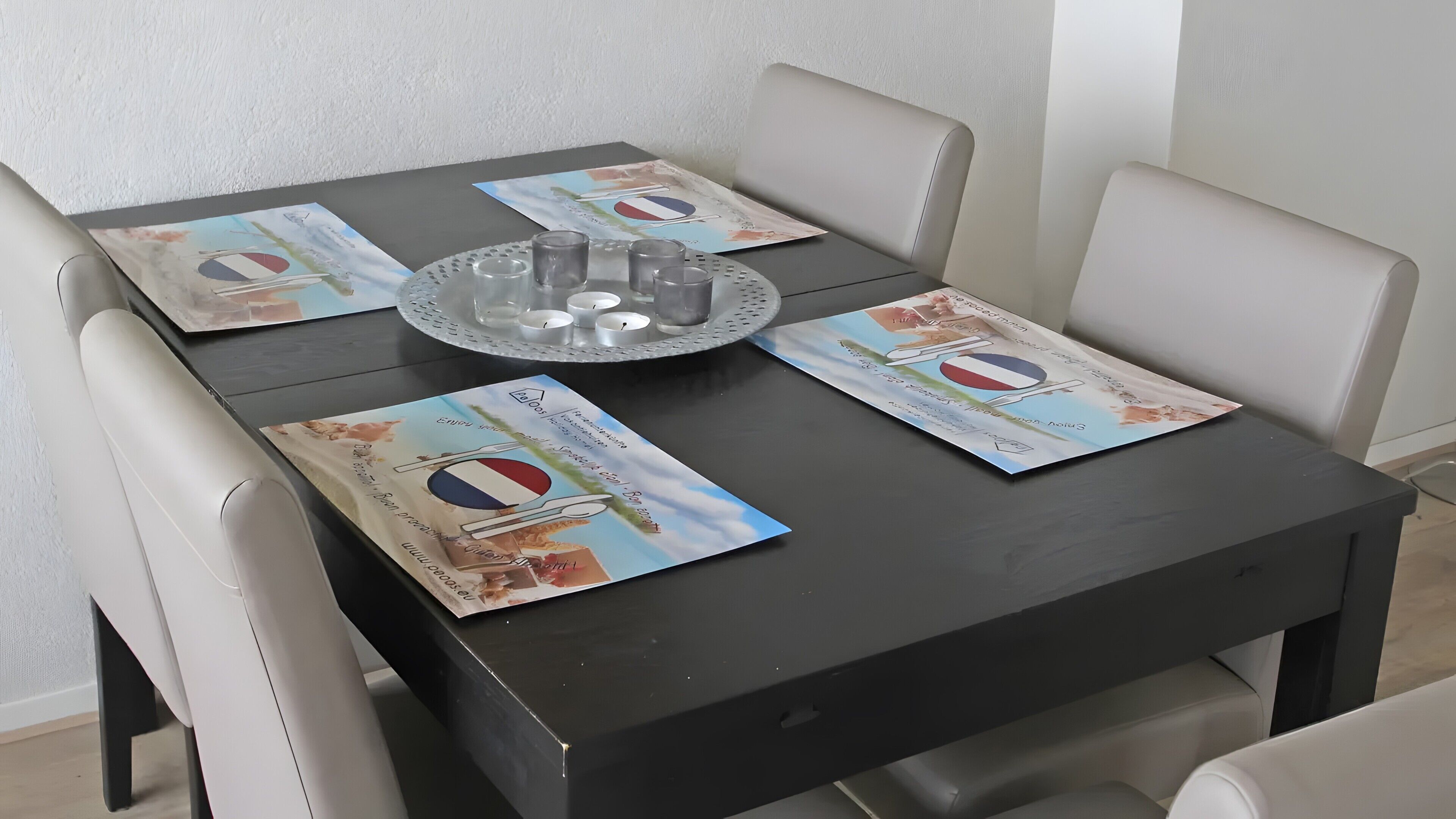 A table with a tray of glasses and candles, surrounded by chairs.