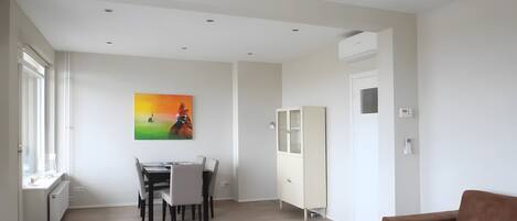 Una sala de estar moderna con comedor, un sofá marrón y un cuadro en la pared.
