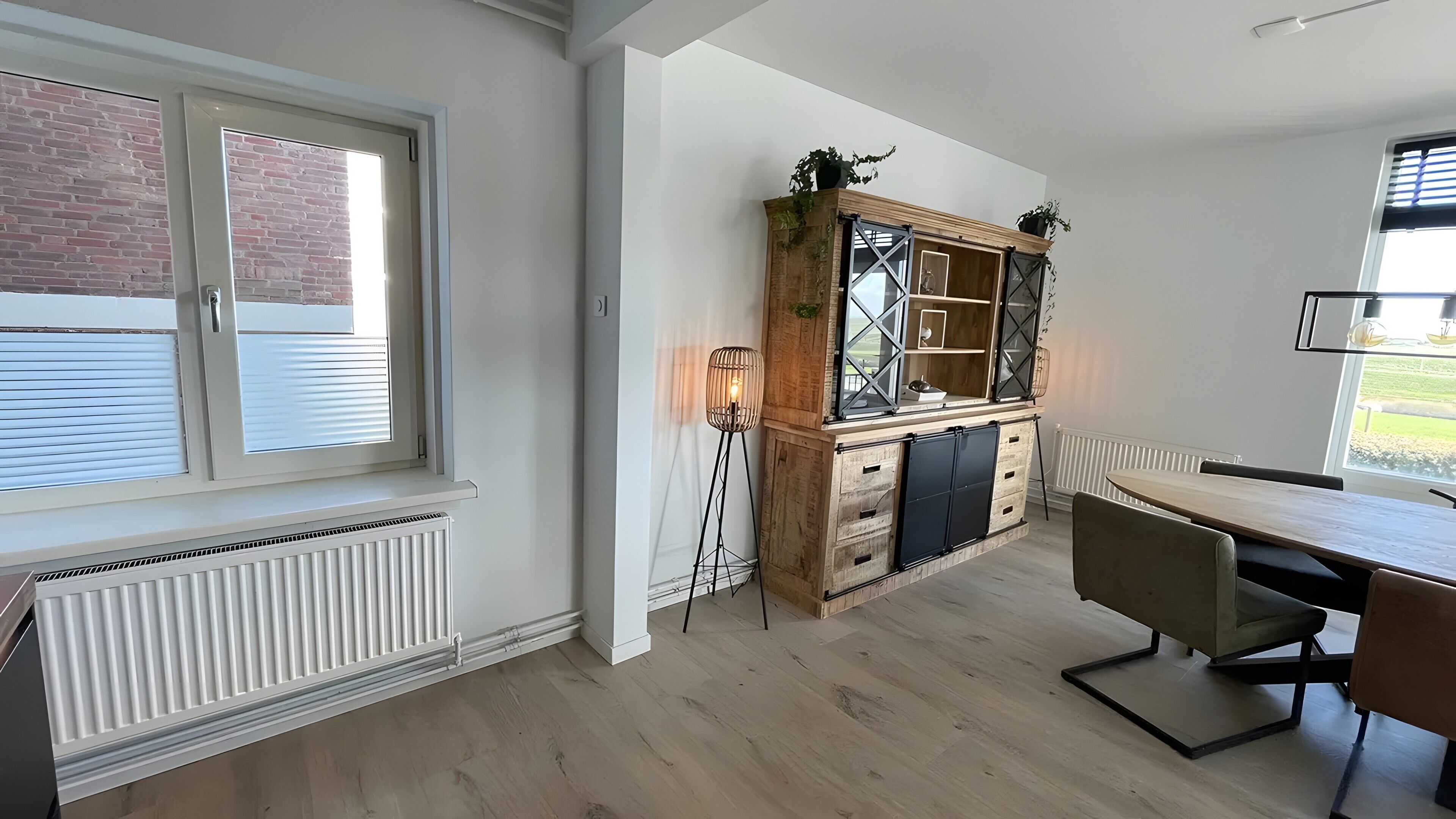 Eine Küche mit Holzschrank, Heizkörper, Esstisch und Fenster mit Jalousien.