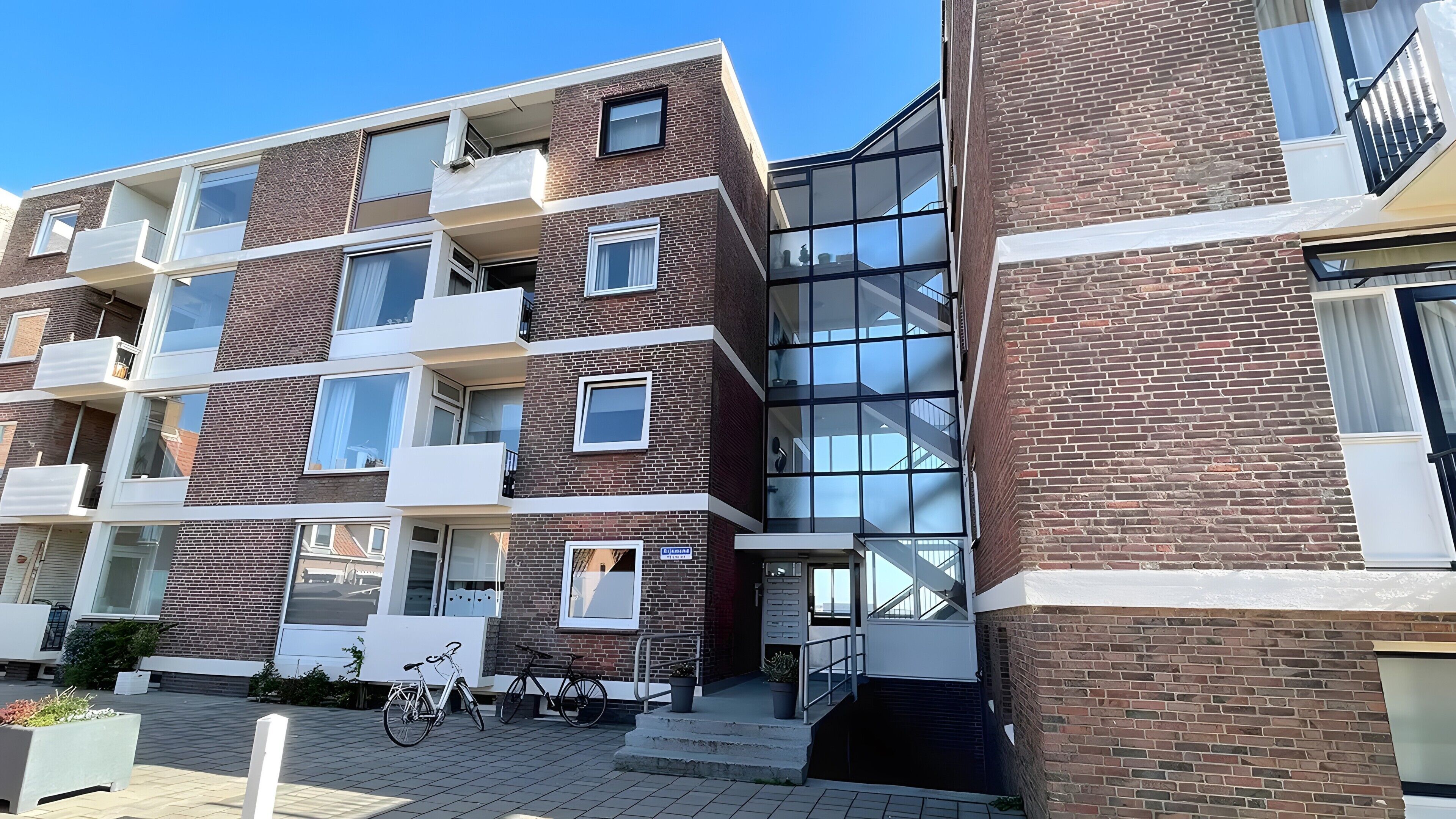 Ein mehrstöckiges Wohngebäude mit Balkonen, großen Fenstern und einer Ziegel-Fassade.
