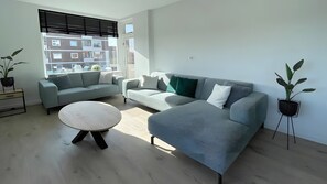 A modern living room with two sofas, a round coffee table, and potted plants.