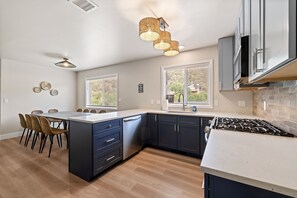 A modern kitchen with a central island, dark cabinetry, a gas stove, and pendant lighting.