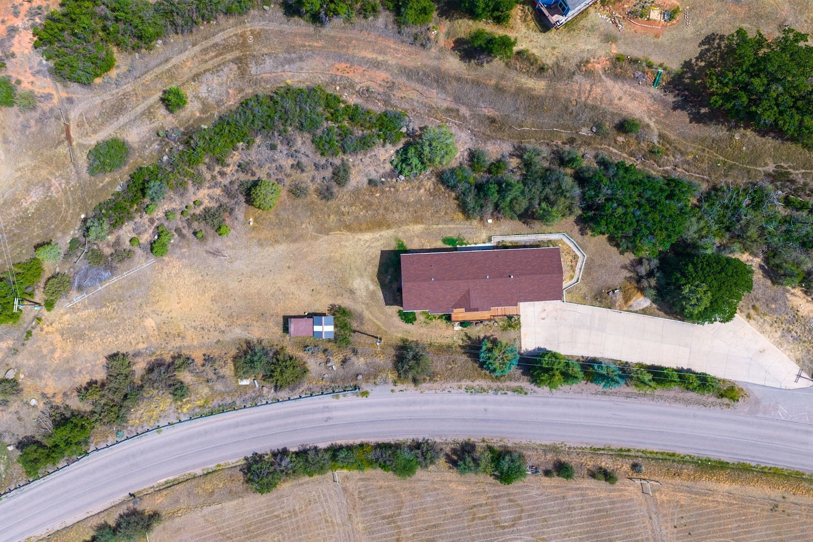 An aerial view of a property with a large building, a smaller structure, and a paved road.