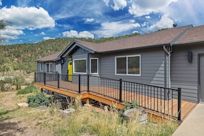 A two-story house with a balcony, a yellow door, and a view of a hilly landscape.