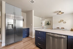 Una cocina moderna con electrodomésticos de acero inoxidable, lavavajillas integrado y encimera blanca.