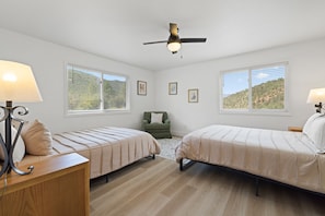 A bedroom with two beds, a ceiling fan, and large windows with a view of a hilly landscape. - Renovated 6BR GWS Escape Near Aspen - A/C (Glenwood Springs)