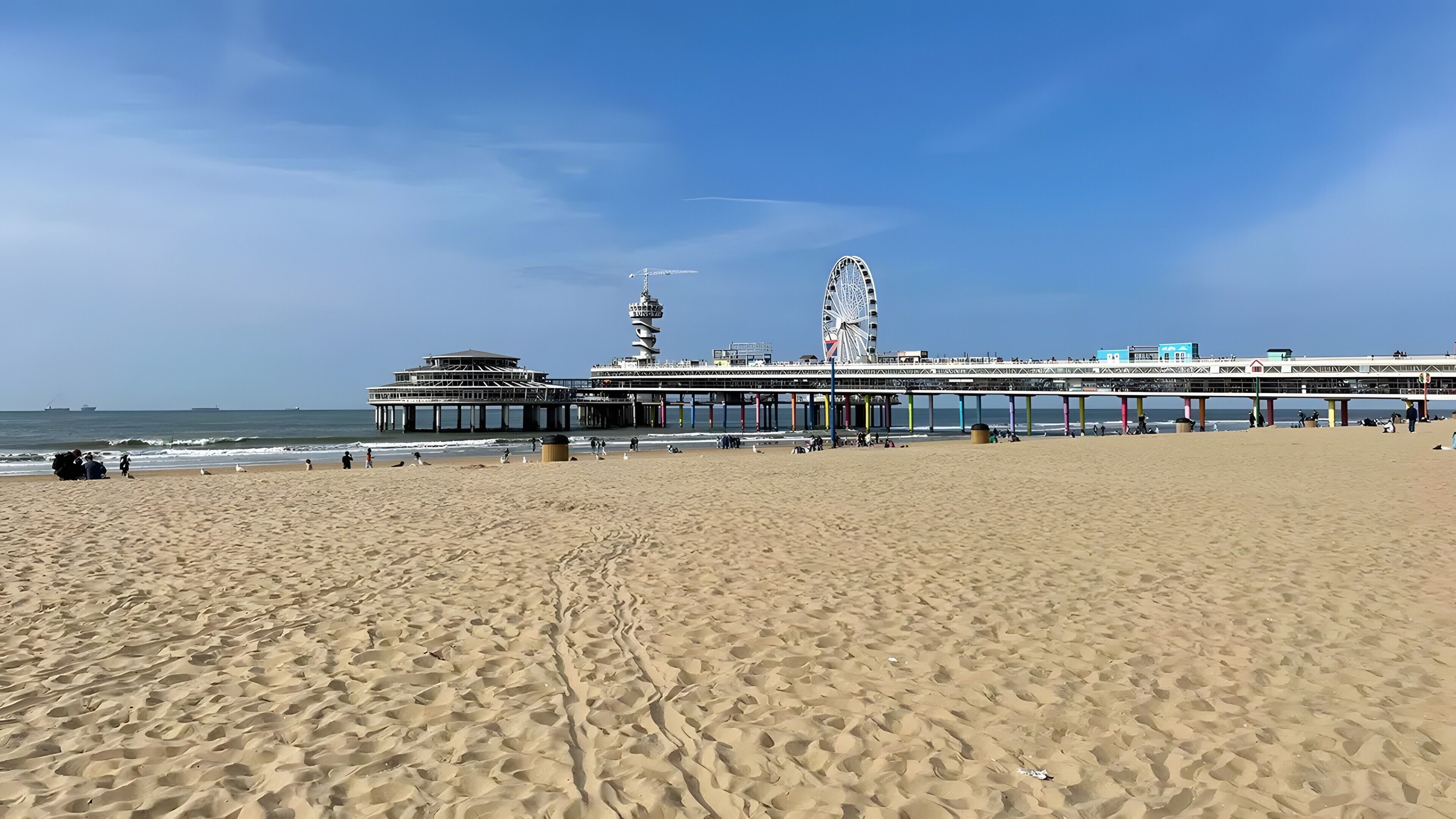 Een strand met een pier, een vuurtoren en een reuzenrad.