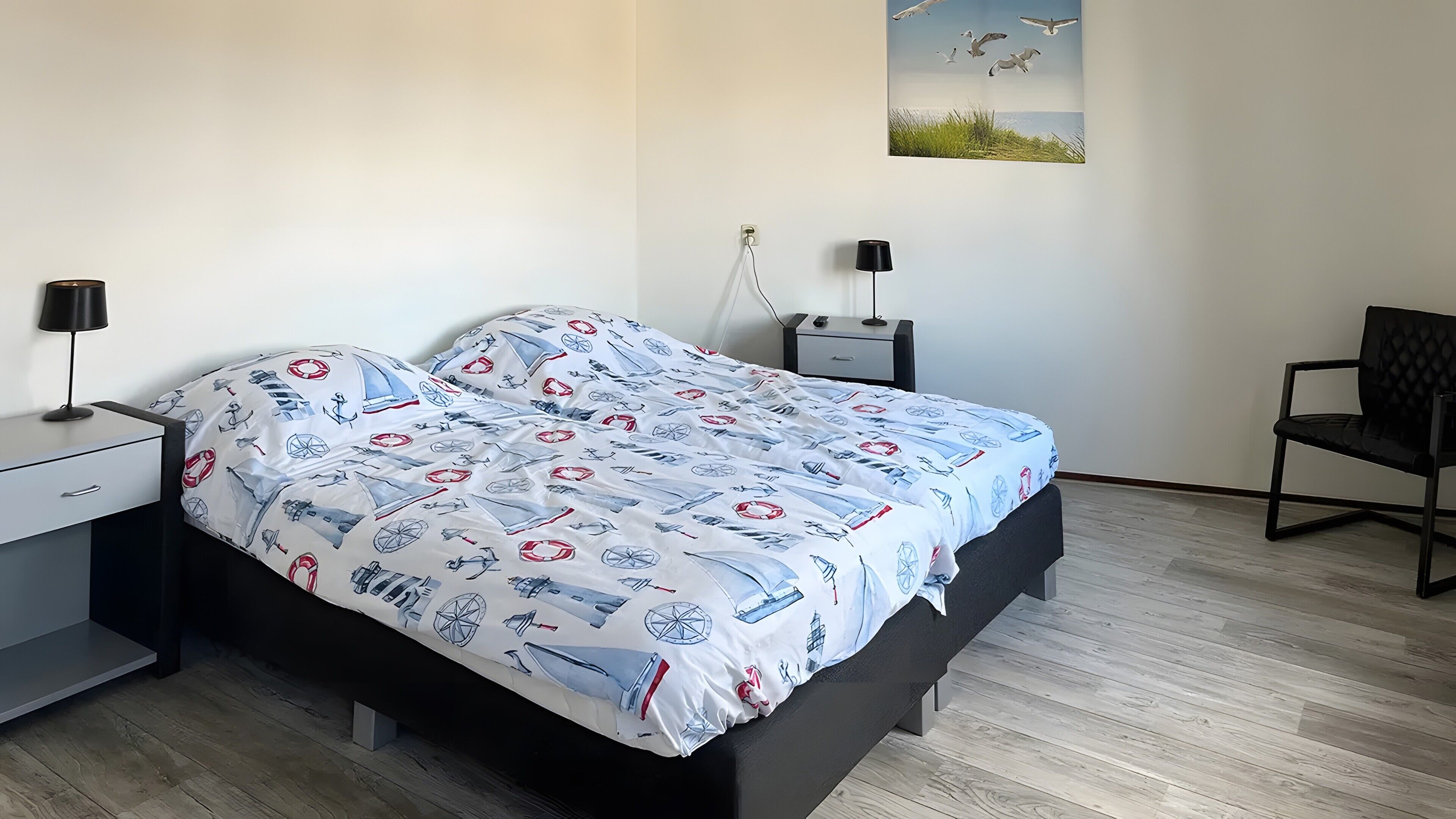 Een slaapkamer met een bed, nachtkastjes, een stoel en een wandlamp.