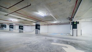 An indoor parking garage with multiple parking bays, each marked with an 'E4' sign, and directional arrows on the floor. - w Enchanting 2BR w Balcony in San Francisco (Panama City)