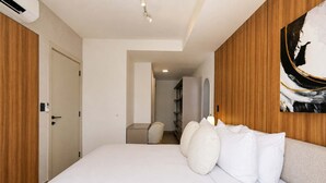 A hotel room with a large bed, a wooden headboard, a painting on the wall, and a door with a light switch. - w Enchanting 2BR w Balcony in San Francisco (Panama City)