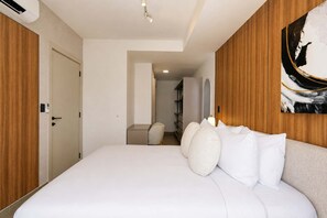 Ein Hotelzimmer mit einem großen Bett, einem Holz-Kopfteil, einem Bild an der Wand und einer Tür mit Lichtschalter.