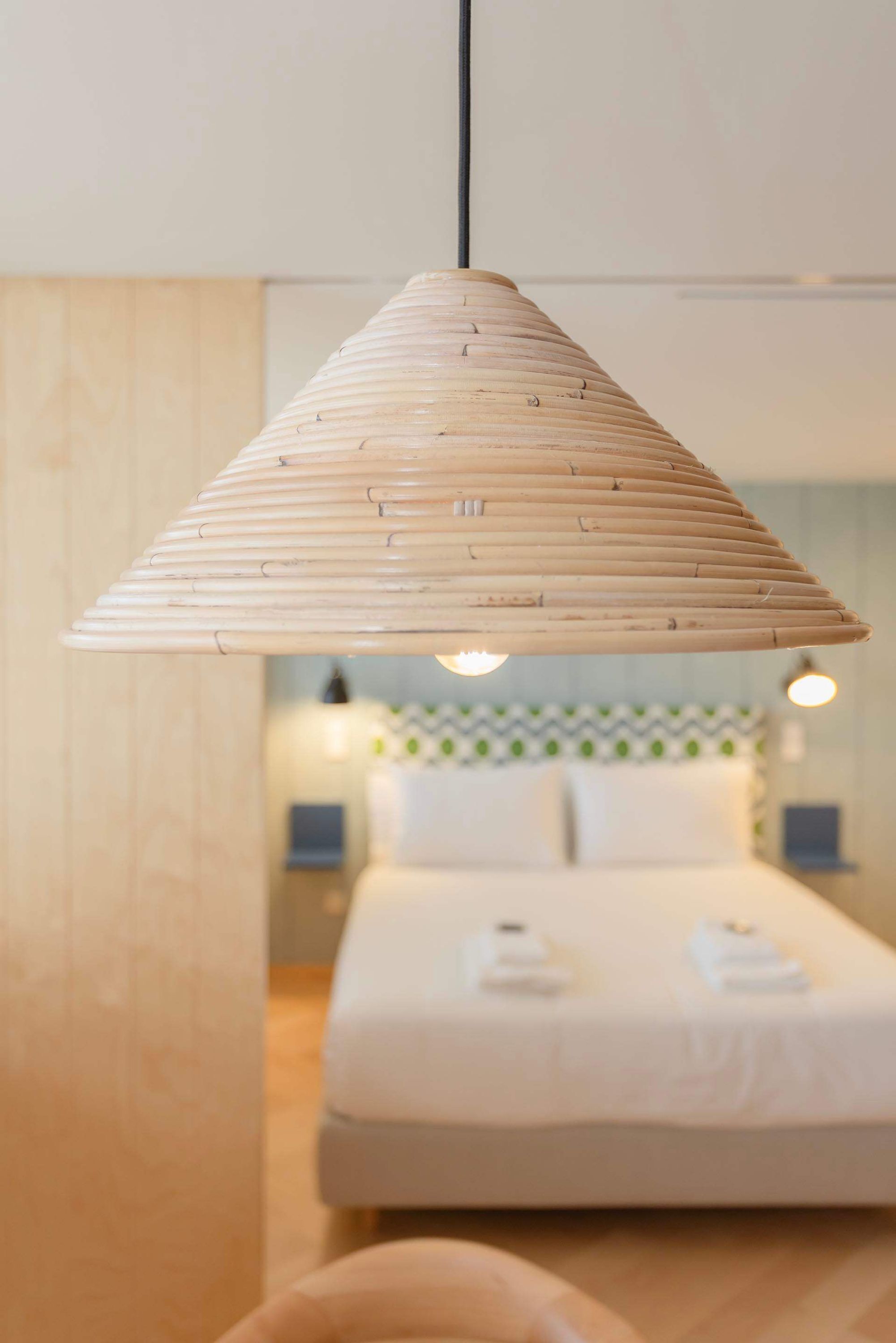 A room with a bed, bedside tables, and a hanging light fixture.