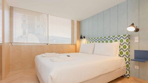 A bedroom with a bed, a window with blinds, a wall-mounted lamp, and a patterned pillow. - Allegro Boutique Apartment 1C by Liiiving (Porto)