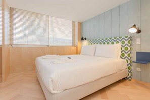 A bedroom with a bed, a window with blinds, a wall-mounted lamp, and a patterned pillow. - Allegro Boutique Apartment 1C by Liiiving (Porto)