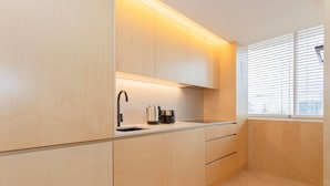 A modern kitchen with wooden cabinets, a stainless steel sink, and a kettle. - Allegro Boutique Apartment 1C by Liiiving (Porto)