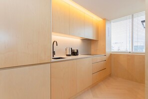 A modern kitchen with wooden cabinets, a stainless steel sink, and a kettle. - Allegro Boutique Apartment 1C by Liiiving (Porto)