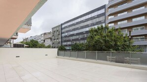 A spacious outdoor terrace with tiled flooring, surrounded by modern buildings with multiple windows and balconies. - Allegro Boutique Apartment 1D by Liiiving (Porto)