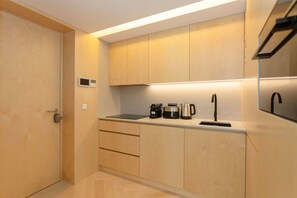 A modern kitchen with wooden cabinets, a built-in oven, a coffee maker, and a kettle. - Allegro Boutique Apartment 1D by Liiiving (Porto)