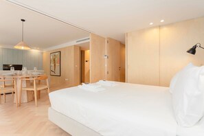 A modern hotel room with a large bed, a dining area with a table and chairs, and a kitchen in the background. - Allegro Boutique Apartment 1D by Liiiving (Porto)