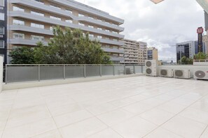 Eine Dachterrasse mit Metallgeländer, Klimaanlagen und Blick auf umliegende Gebäude.