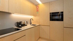 A modern kitchen with wooden cabinets, a built-in oven, a coffee machine, and a sink. - Allegro Boutique Apartment 1D by Liiiving (Porto)