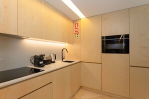 Eine moderne Küche mit Holzausstattung, Backofen, Kaffeemaschine und Spüle.