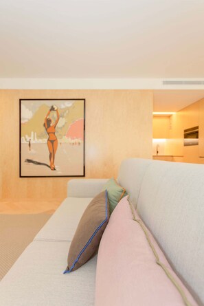 Ein modernes Wohnzimmer mit einer Couch, Kissen und einem gerahmten Kunstwerk an der Wand.