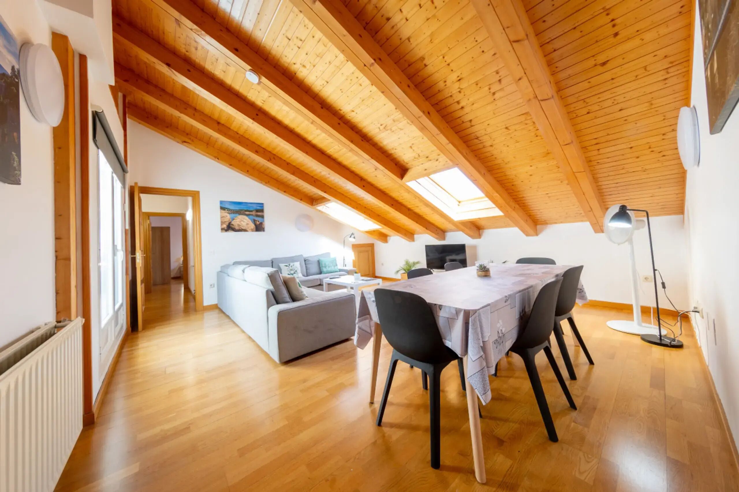 Un loft spacieux avec un haut plafond en bois, un coin repas avec une table et des chaises, un canapé et un téléviseur.
