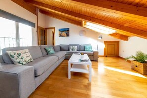 A modern living room with a sectional sofa, a white coffee table, and a wooden ceiling.
