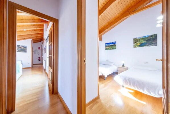 A room with a wooden ceiling, a bed, a nightstand, and a wall-mounted picture.