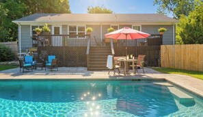 A backyard with a swimming pool, a wooden deck, and outdoor furniture.