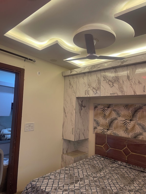 A bedroom with a bed, a ceiling fan, and a marble-patterned cabinet.