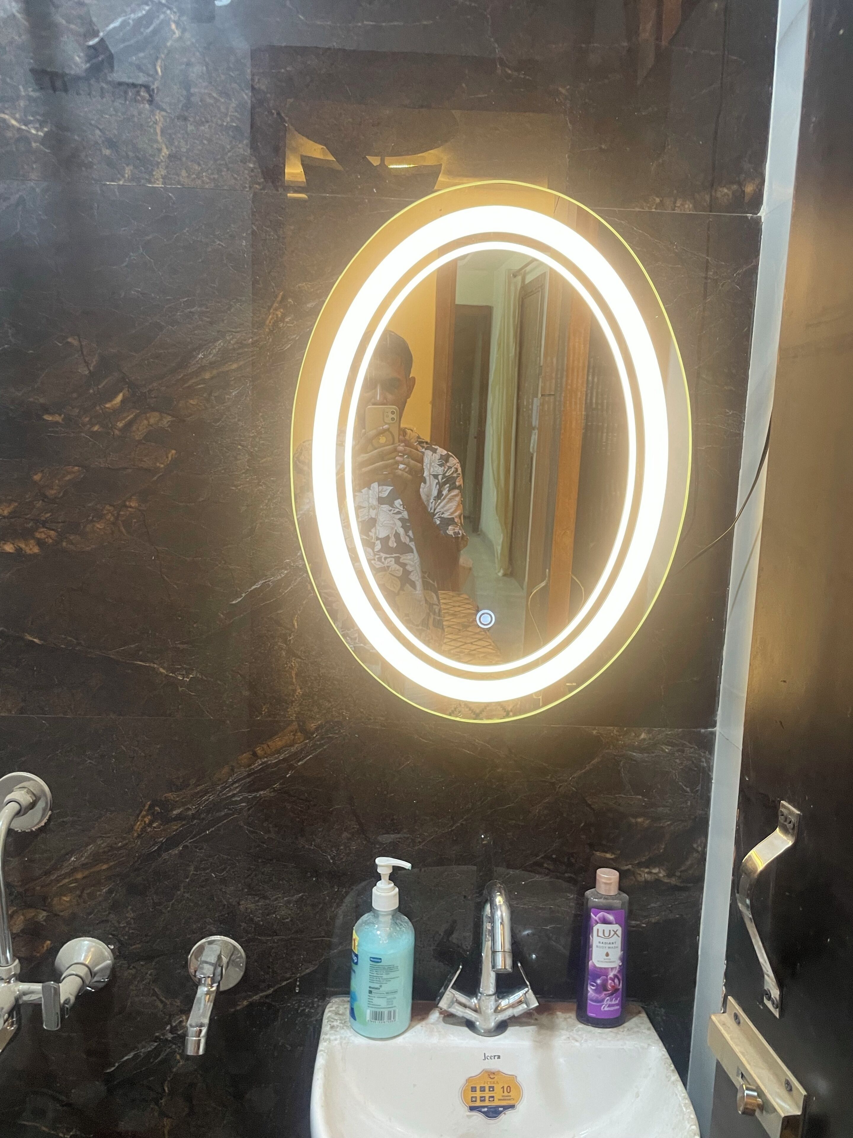 Une salle de bain avec un lavabo en marbre, un miroir avec un éclairage intégré et une douche.