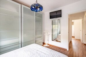 A bedroom with a bed, a TV mounted on the wall, and a wardrobe with frosted glass doors. - Holiday Home 'Villa La Mayorazga Cozy Cottage' with Private Pool, Private Terrace and Wi-Fi (Pago del Humo)