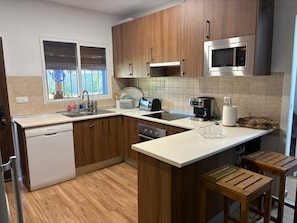 A modern kitchen with wooden cabinets, a built-in microwave, a coffee maker, and a dishwasher. - Holiday Home 'Villa La Mayorazga Cozy Cottage' with Private Pool, Private Terrace and Wi-Fi (Pago del Humo)