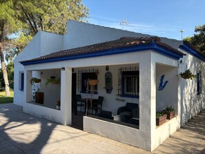 A small, single-story building with a tiled roof, a covered patio area with seating, and hanging plants. - Holiday Home 'Villa La Mayorazga Cozy Cottage' with Private Pool, Private Terrace and Wi-Fi (Pago del Humo)