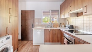 A compact kitchen with wooden cabinets, a dishwasher, a toaster, and a window with blinds. - Holiday Home 'Villa La Mayorazga Cozy Cottage' with Private Pool, Private Terrace and Wi-Fi (Pago del Humo)
