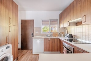 A compact kitchen with wooden cabinets, a dishwasher, a toaster, and a window with blinds. - Holiday Home 'Villa La Mayorazga Cozy Cottage' with Private Pool, Private Terrace and Wi-Fi (Pago del Humo)